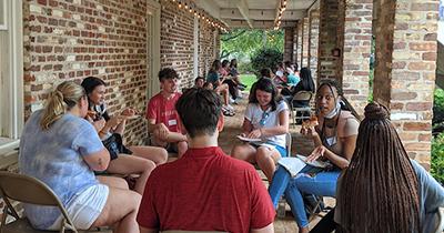 Students sitting outside at tables on campus.